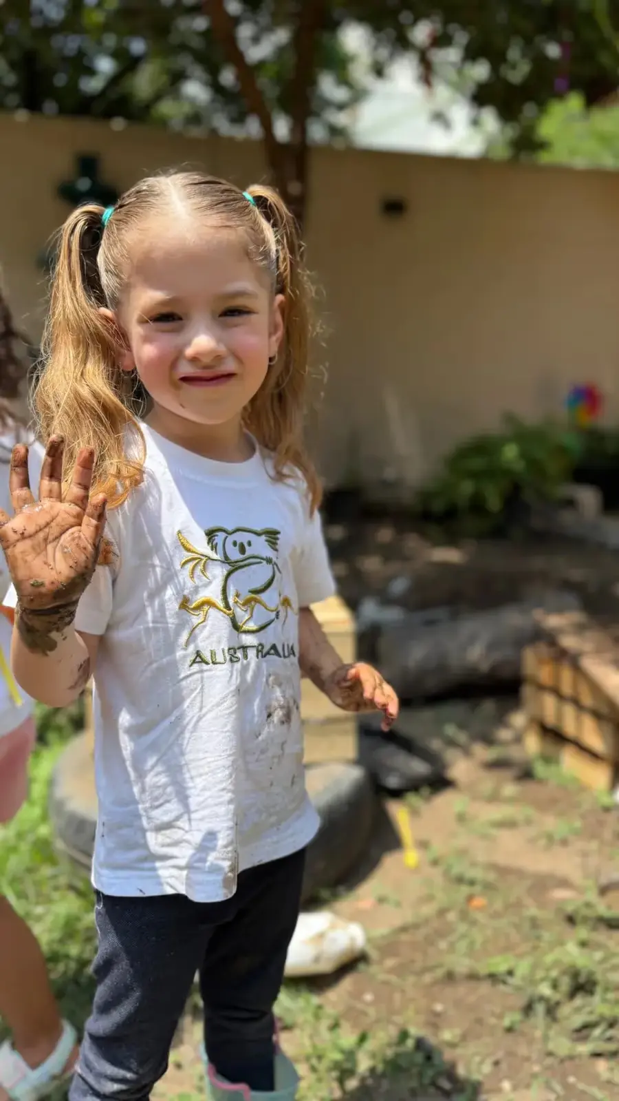 Niña mostrando su mano con tierra después de explorar el jardín
